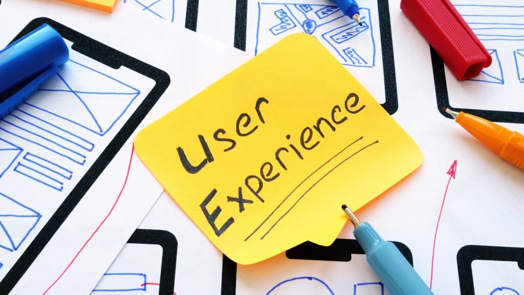 Post-it jaune avec l'inscription "User Experience" sur des croquis d'interface.