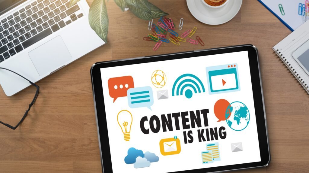 Tablette posée sur un bureau avec un message "Content is King" à l'écran, entourée de fournitures de bureau.