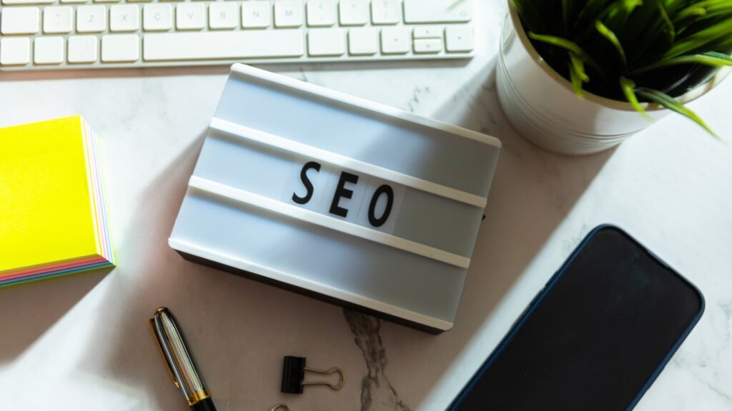 Plaque lumineuse avec les lettres "SEO" sur un bureau, entourée de fournitures de bureau.