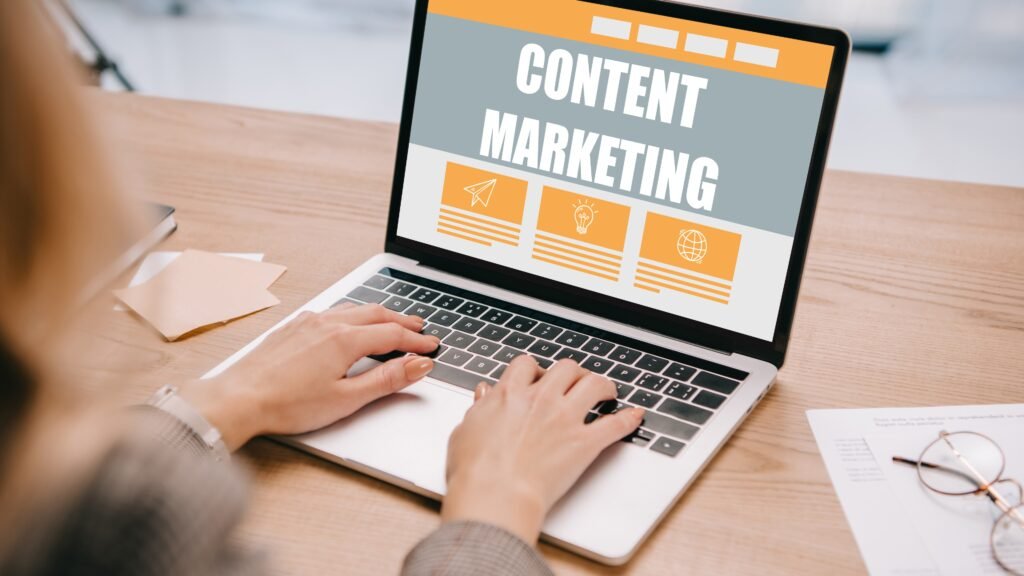 Personne utilisant un ordinateur portable affichant "Content Marketing", entourée de documents et de graphiques.