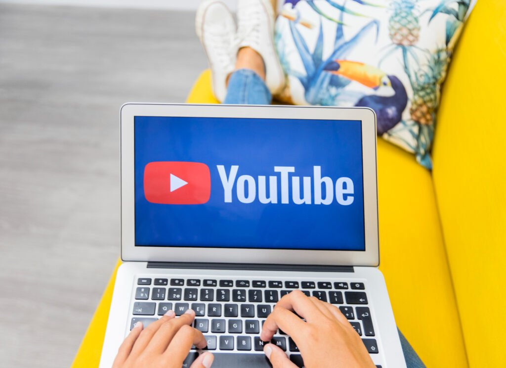 Personne utilisant un ordinateur portable affichant le logo YouTube, symbolisant le travail d’optimisation du SEO des vidéos YouTube.